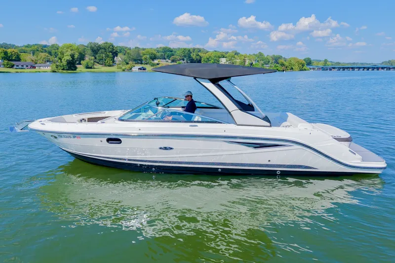 Slide: The Image of 2019 Sea Ray SLX 280 boat cruising on a serene lake under a clear blue sky. - 2