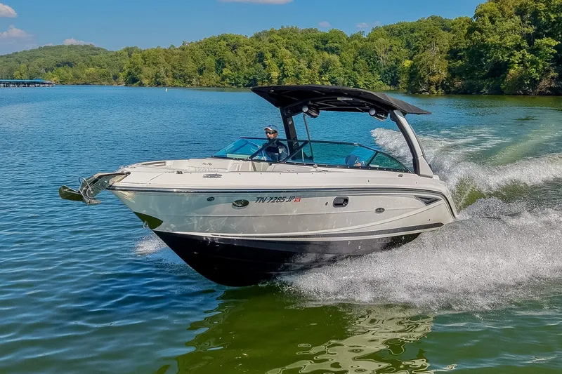 Slide: The Image of 2019 Sea Ray SLX 280 cruising on a scenic lake with lush green shoreline. - 9