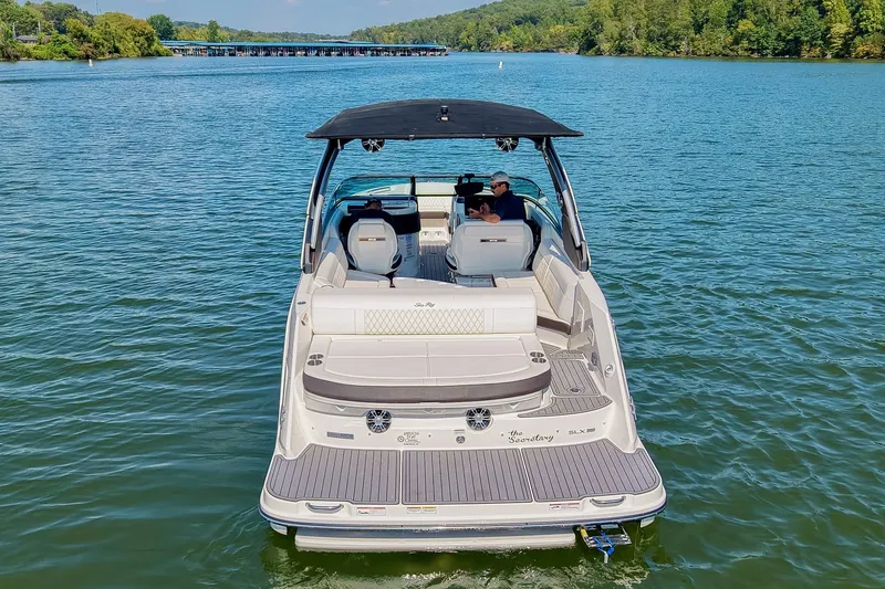 Slide: The Image of 2019 Sea Ray SLX 280 boat cruising on a serene lake with lush green surroundings. - 5