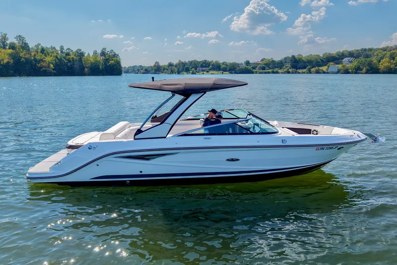 Slide: The Image of 2019 Sea Ray SLX 280 boat cruising on a serene lake under a clear blue sky. - 6