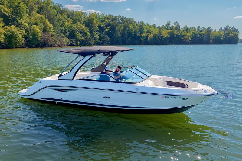 Slide: The Image of 2019 Sea Ray SLX 280 boat cruising on a serene lake with lush green forest backdrop. - 7