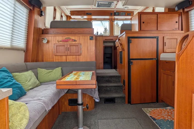 Slide: The Image of Interior of a 2003 Nordic Tug 37, featuring cozy seating and wooden cabinetry. - 12