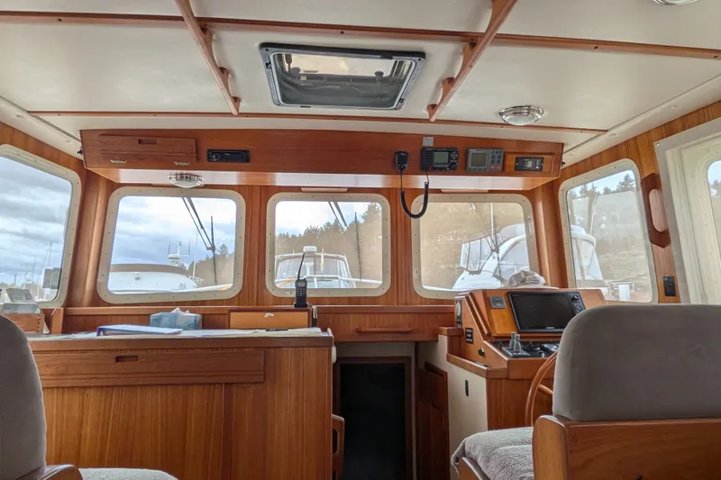 Slide: The Image of Interior of a 2003 Nordic Tug 37 boat, featuring a wooden helm and navigation equipment. - 20