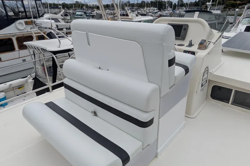 Slide: The Image of 2003 Nordic Tug 37 boat helm with white seating and marina background. - 7