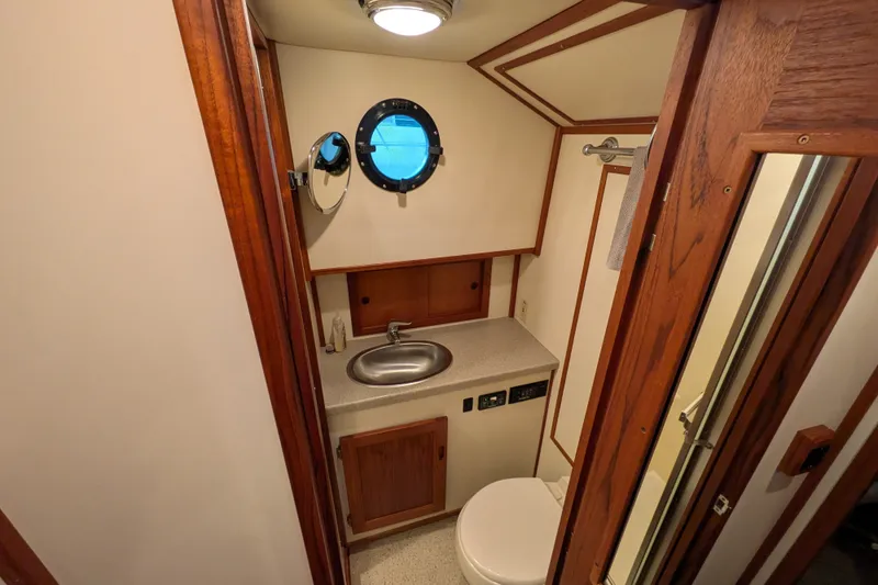 Slide: The Image of Bathroom interior of 2003 Nordic Tug 37 with sink, toilet, and porthole window. - 37