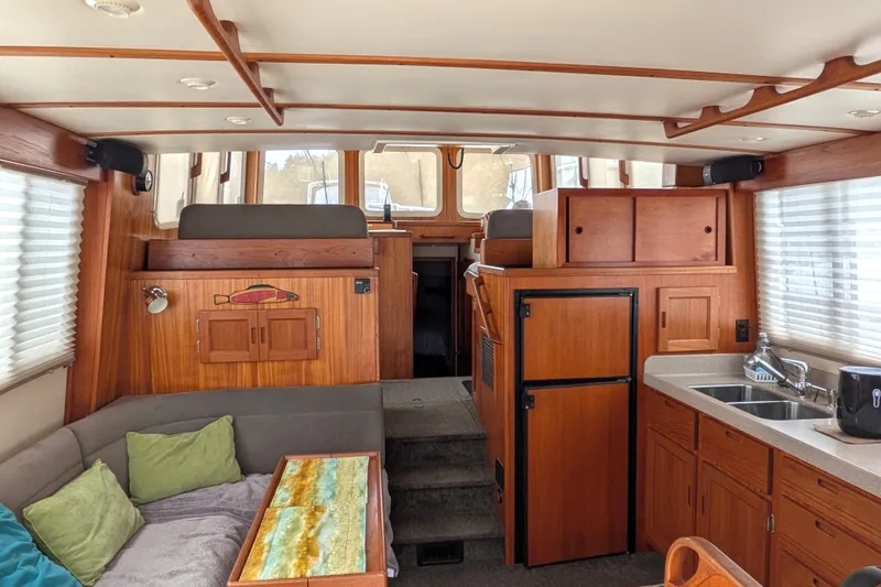 Slide: The Image of Interior of a 2003 Nordic Tug 37, featuring wood cabinetry, seating, and a compact kitchen area. - 13