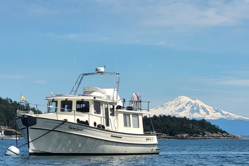 The Image of 2003 Nordic Tug 37 boat on water with scenic mountain backdrop. - 0