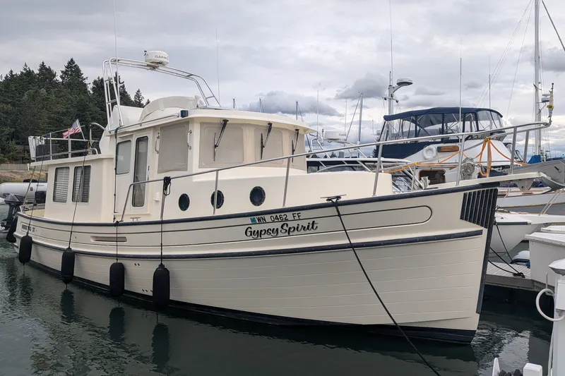 Slide: The Image of 2003 Nordic Tug 37 docked in marina, overcast sky, surrounded by other boats. - 1