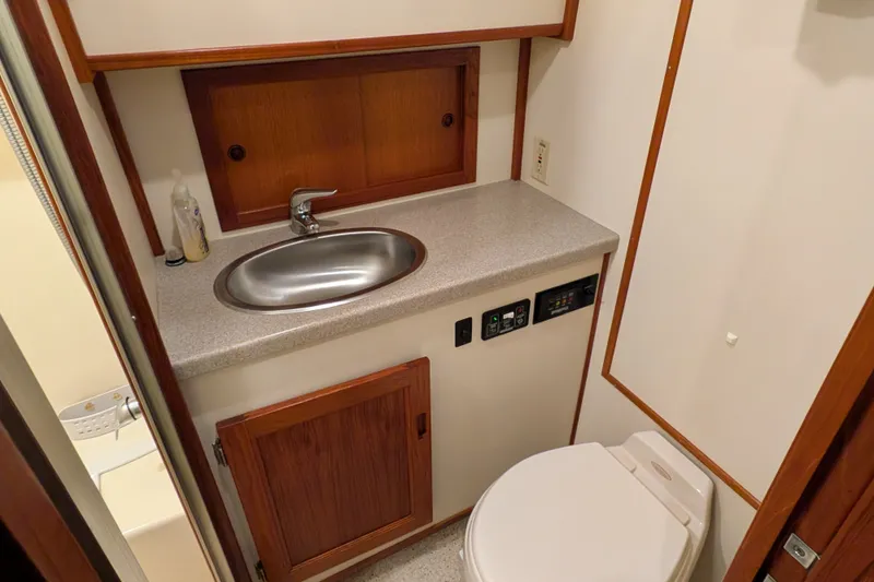 Slide: The Image of Bathroom interior of 2003 Nordic Tug 37 with sink, toilet, and wooden cabinetry. - 38