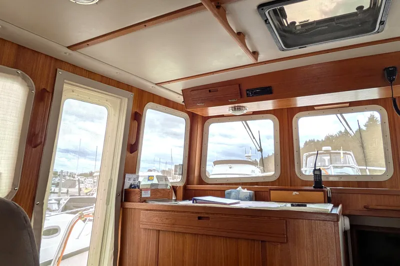 Slide: The Image of Interior view of a 2003 Nordic Tug 37, showcasing wooden cabinetry and large windows. - 22