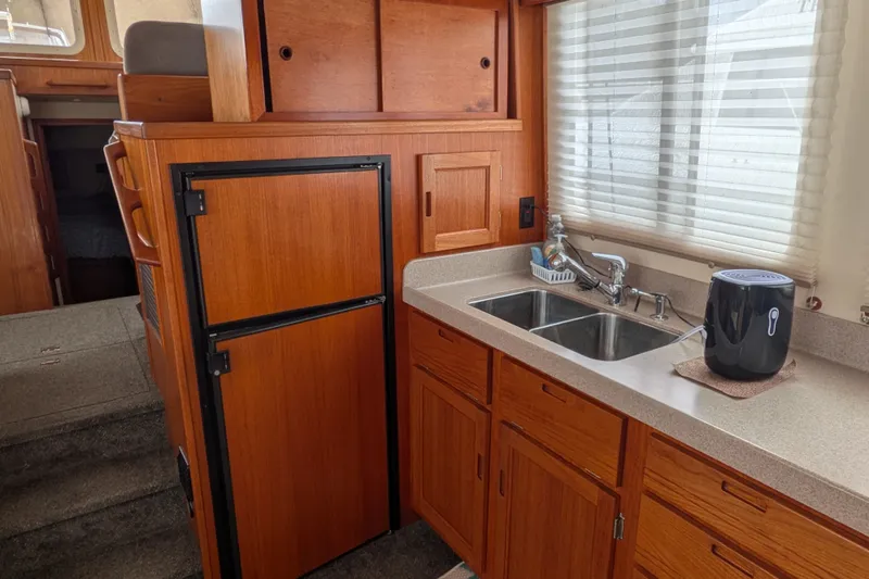 Slide: The Image of 2003 Nordic Tug 37 interior kitchen with wooden cabinets, dual sink, and compact refrigerator. - 16