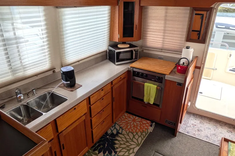 Slide: The Image of Interior of 2003 Nordic Tug 37, featuring a well-equipped kitchen with wooden cabinetry. - 19
