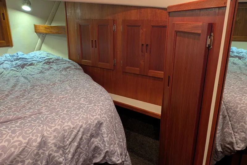 Slide: The Image of Cozy cabin interior of a 2003 Nordic Tug 37 with wooden cabinetry and patterned bedding. - 42