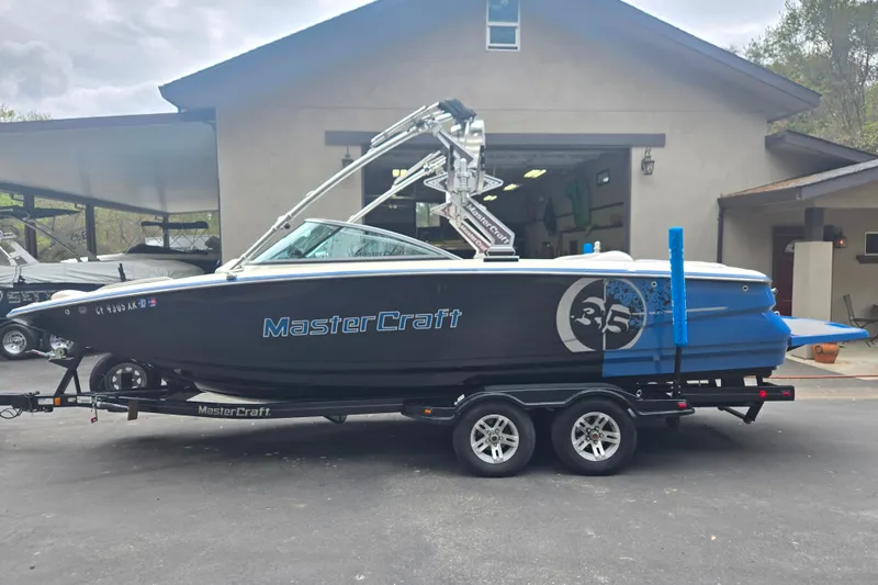 Slide: The Image of 2008 MasterCraft X-35 boat on trailer, parked outside a garage. - 2