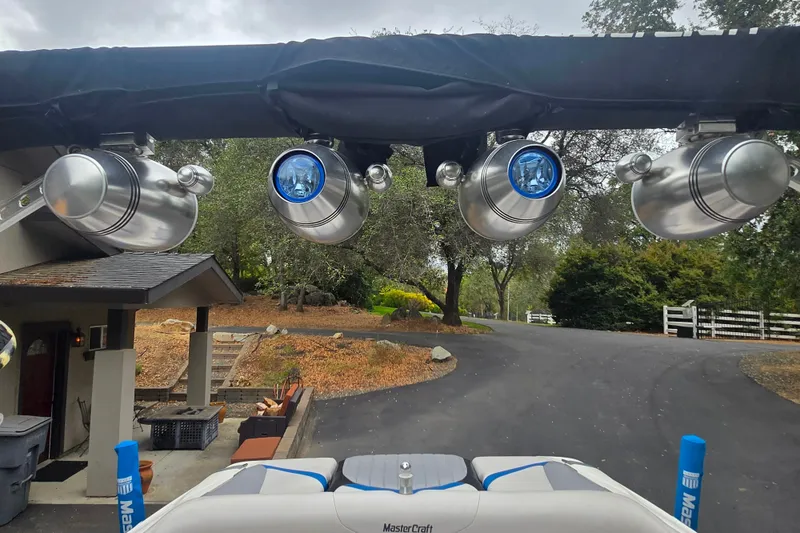 Slide: The Image of 2008 MasterCraft X-35 boat with mounted speakers, parked in a driveway surrounded by trees. - 19