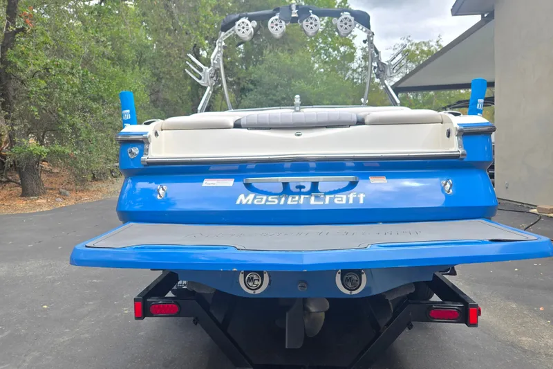 Slide: The Image of 2008 MasterCraft X-35 boat, blue exterior, parked on a driveway with trees in the background. - 3