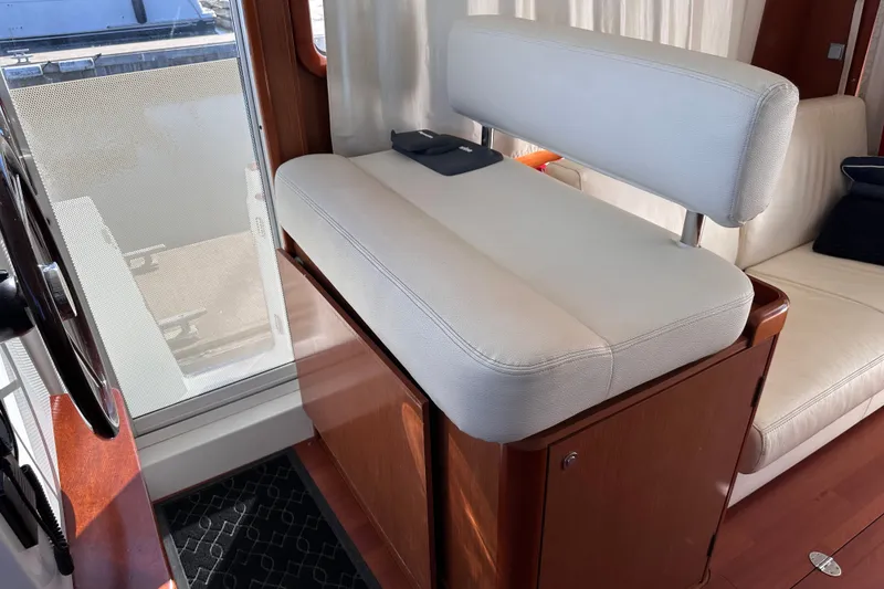 Slide: The Image of Interior helm seat of 2011 Beneteau Swift Trawler 34, featuring white upholstery and wooden accents. - 42