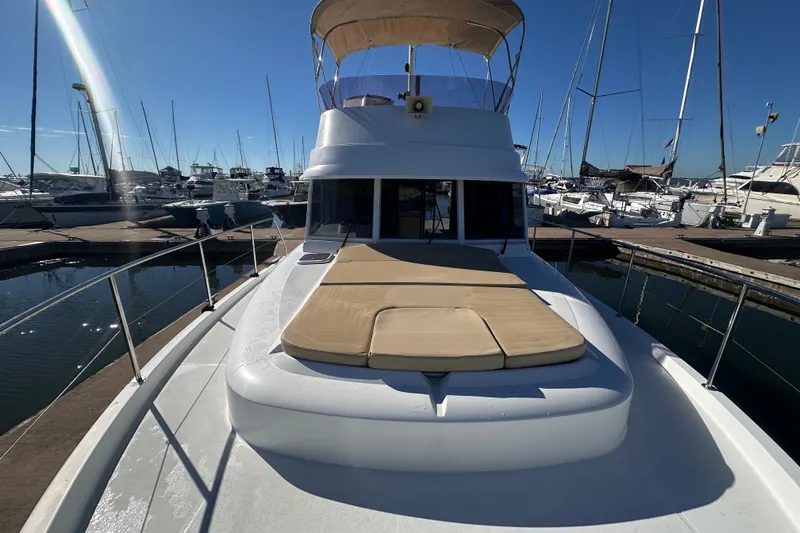 Slide: The Image of 2011 Beneteau Swift Trawler 34 docked at marina, showcasing spacious deck and sunbathing area. - 13