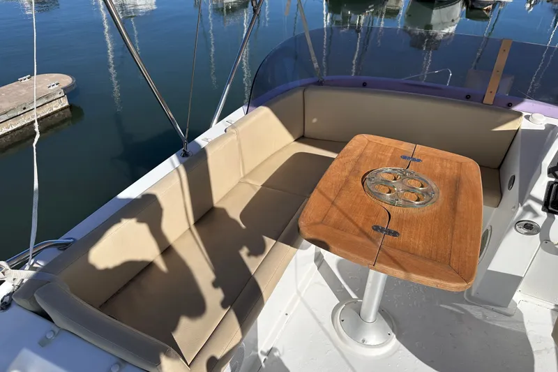 Slide: The Image of 2011 Beneteau Swift Trawler 34 interior with beige seating and wooden table, docked at marina. - 22