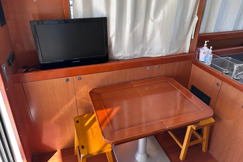 Slide: The Image of Interior of 2011 Beneteau Swift Trawler 34 with TV, wooden table, and kitchenette. - 34