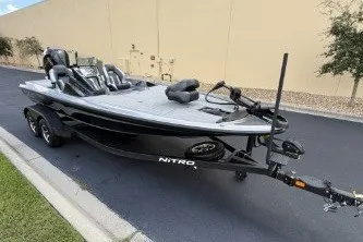 Slide: The Image of 2027 Nitro Z20 XL boat on trailer, parked on asphalt near beige wall. - 2