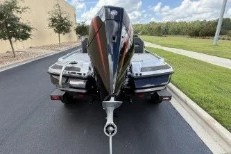 Slide: The Image of 2027 Nitro Z20 XL boat, rear view, parked on a paved road with grassy surroundings. - 6