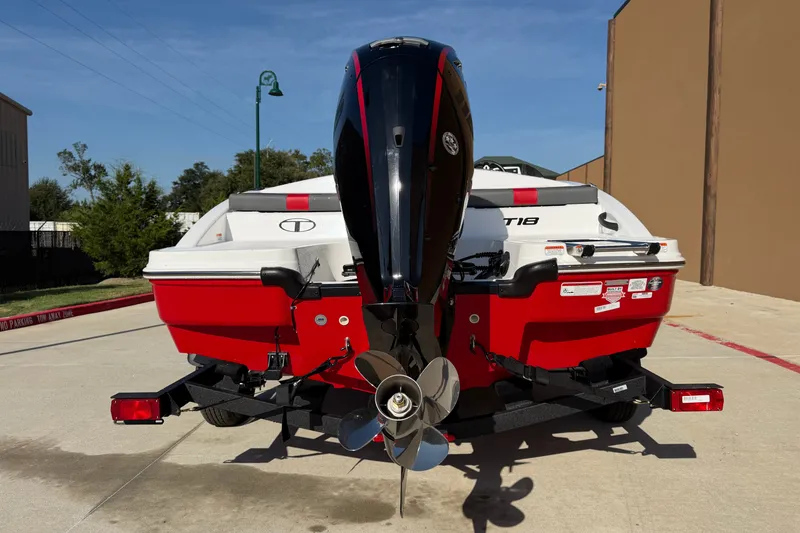 Slide: The Image of 2027 Tahoe T18 boat with outboard motor, red and white design, parked outdoors. - 13