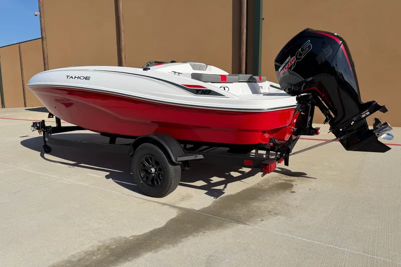 The Image of 2027 Tahoe T18 boat with red and white design on a trailer, parked outdoors. - 0