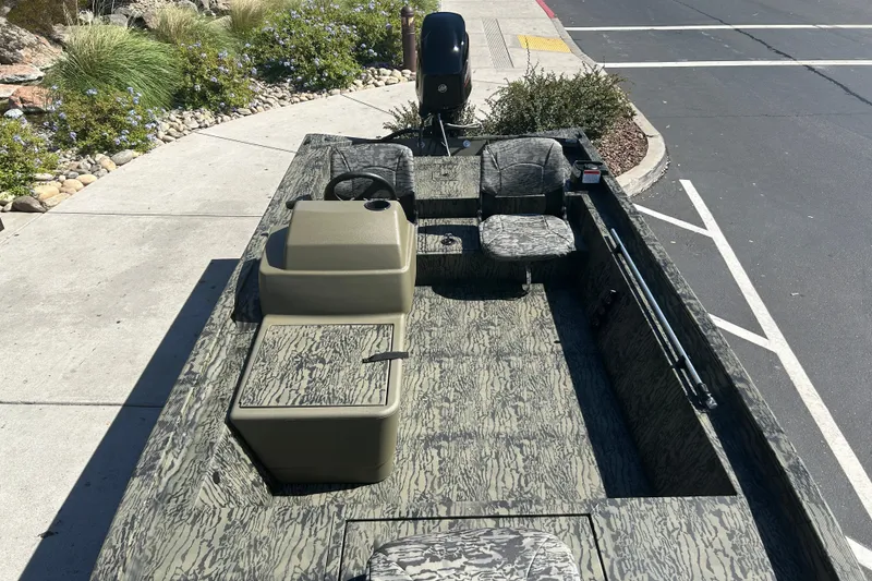 Slide: The Image of 2027 Tracker Grizzly 1754 SC boat with camouflage design, parked on a street. - 14