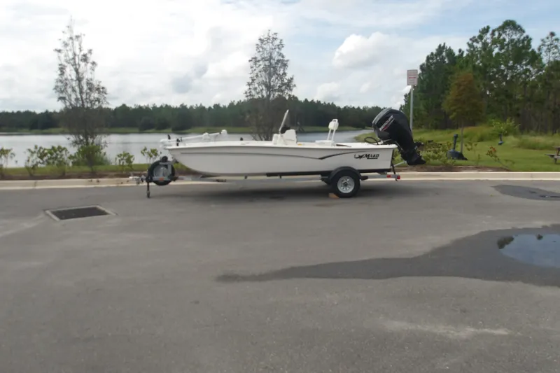 Slide: The Image of 2027 Mako Pro Skiff 17 CC boat on trailer near a scenic lake backdrop. - 2