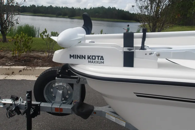 Slide: The Image of 2027 Mako Pro Skiff 17 CC with Minn Kota Maxxum trolling motor by a lake. - 13