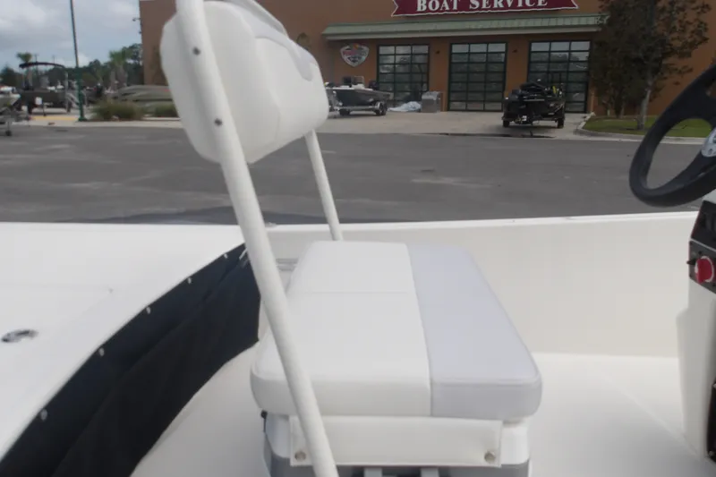Slide: The Image of 2027 Mako Pro Skiff 17 CC boat interior with white seating near a boat service center. - 11