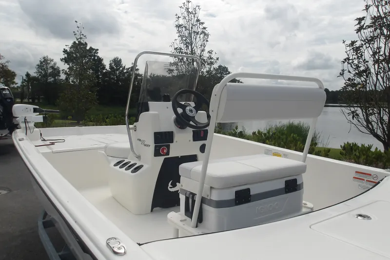Slide: The Image of 2027 Mako Pro Skiff 17 CC boat with center console, near a serene lake. - 12