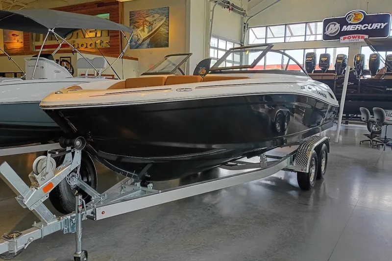 The Image of 2027 Tahoe 210 S boat on trailer in showroom, featuring sleek black design. - 0