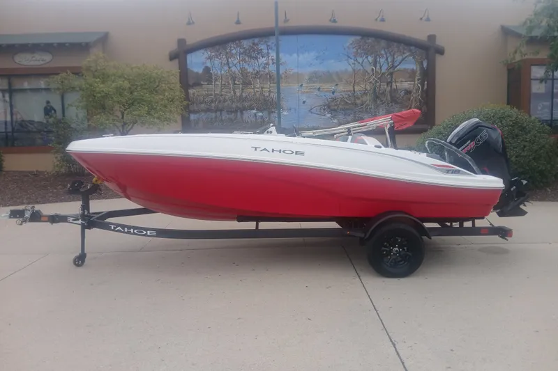 The Image of 2027 Tahoe T18 boat in red and white on a trailer, parked outdoors. - 0