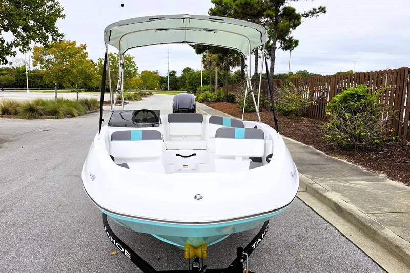 Slide: The Image of 2027 Tahoe T16 boat with canopy, parked on a paved road, surrounded by greenery. - 7