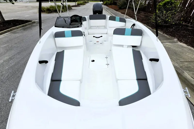 Slide: The Image of 2027 Tahoe T16 boat interior with white and gray seating, parked on a street. - 13