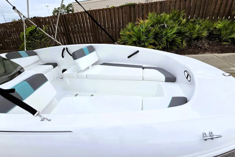 Slide: The Image of 2027 Tahoe T16 boat interior with white and gray seating, docked near wooden fence. - 14