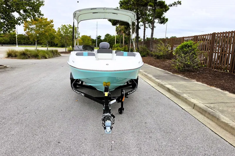 Slide: The Image of 2027 Tahoe T16 boat on trailer in parking lot, surrounded by trees and fence. - 8