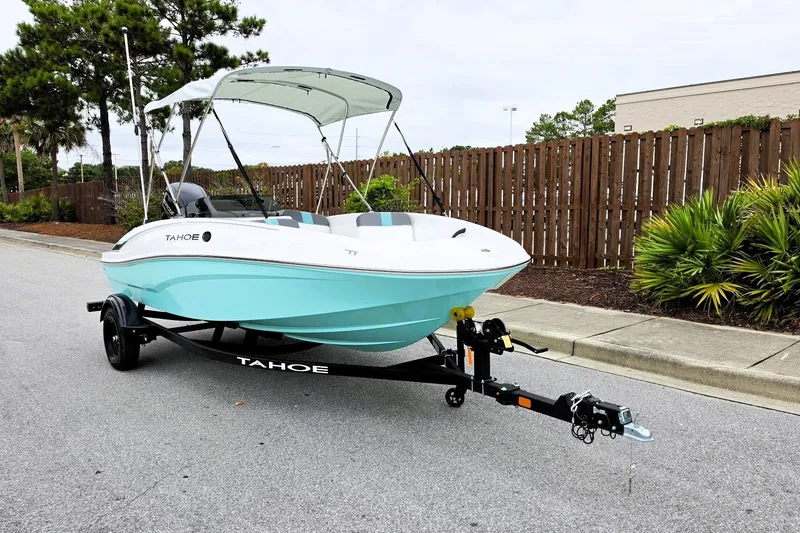Slide: The Image of 2027 Tahoe T16 boat on trailer, parked on street with trees and fence background. - 6
