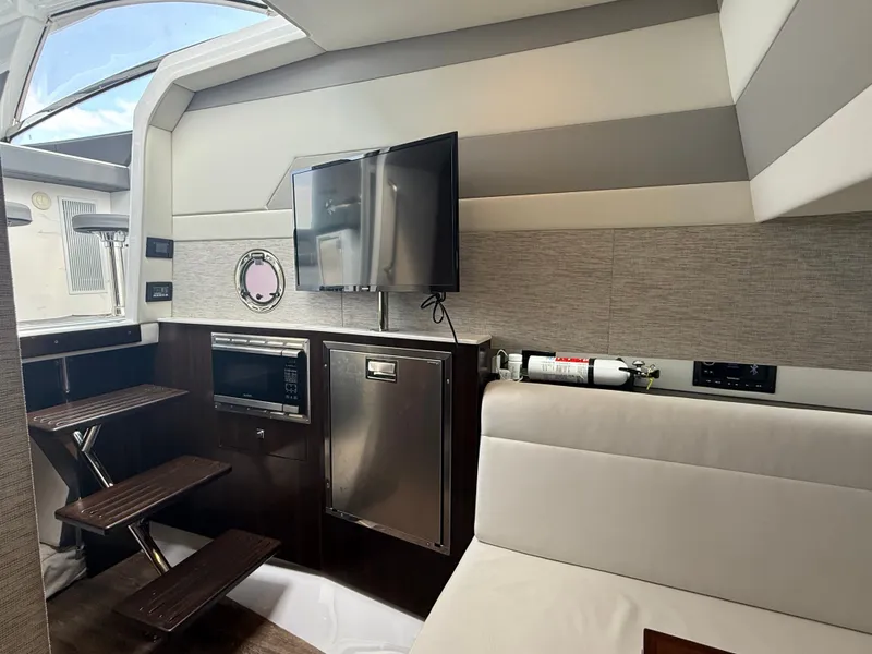 Slide: The Image of Interior of a modern yacht with a TV, microwave, and fridge. Dark wood steps and white upholstery. - 27