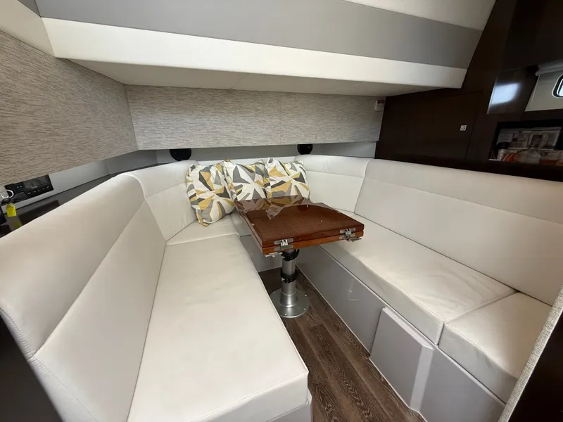 Slide: The Image of Interior of a 2021 Cruisers Yachts 42 GLS OB with white upholstery and a wooden table. - 24