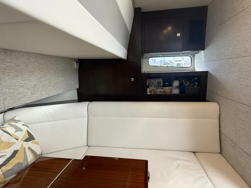 Slide: The Image of Interior of a 2021 Cruisers Yachts 42 GLS OB with a white sofa and wooden table. - 26