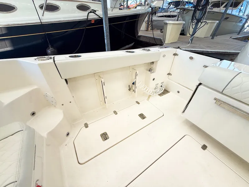 Slide: The Image of The image shows the cockpit of a Pursuit OS 325 Offshore boat. It features a clean, white surface with multiple storage compartments and a cushioned seating area. - 23