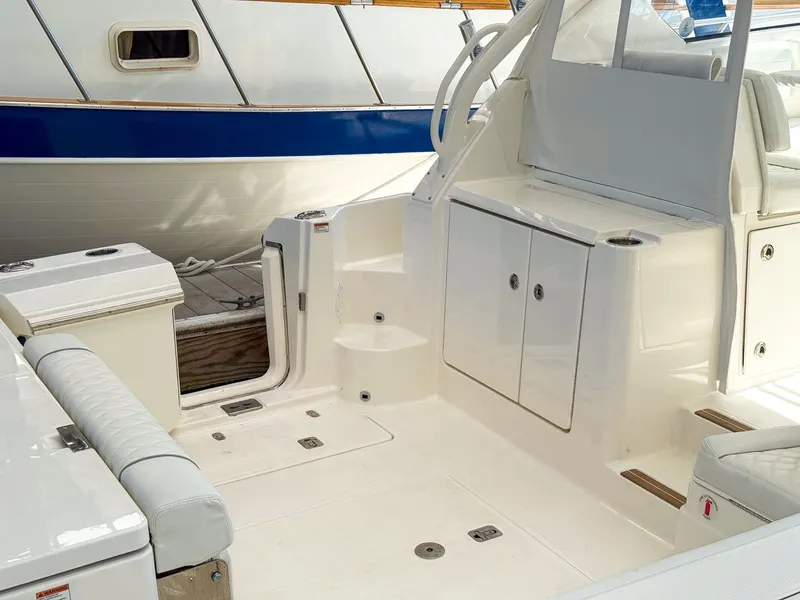 Slide: The Image of The image shows the cockpit of a Pursuit OS 325 Offshore boat. It features white upholstery and storage. - 6