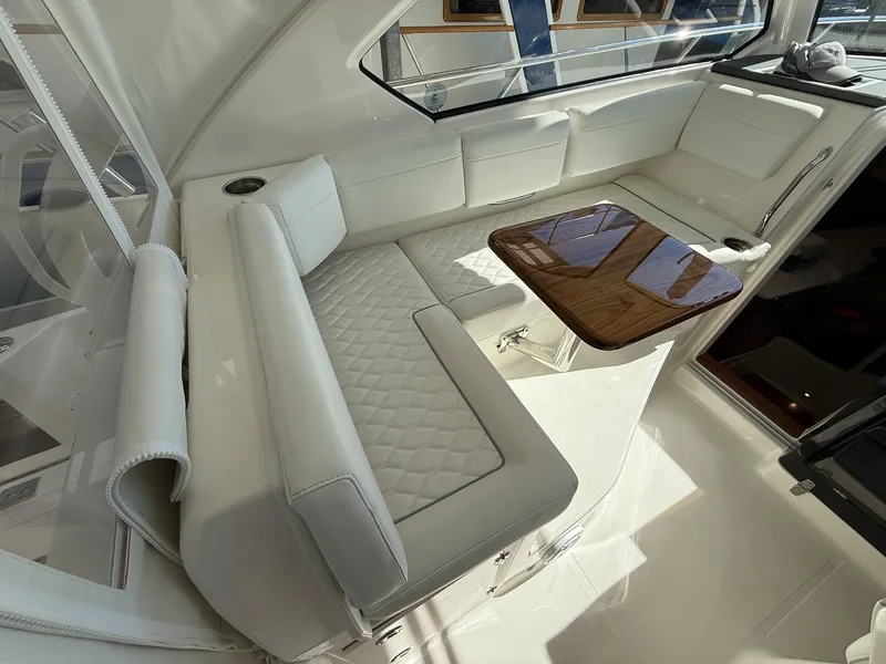 Slide: The Image of The 2026 Pursuit OS 325 Offshore cabin features an elegant white leather seating area with a wooden table. - 49