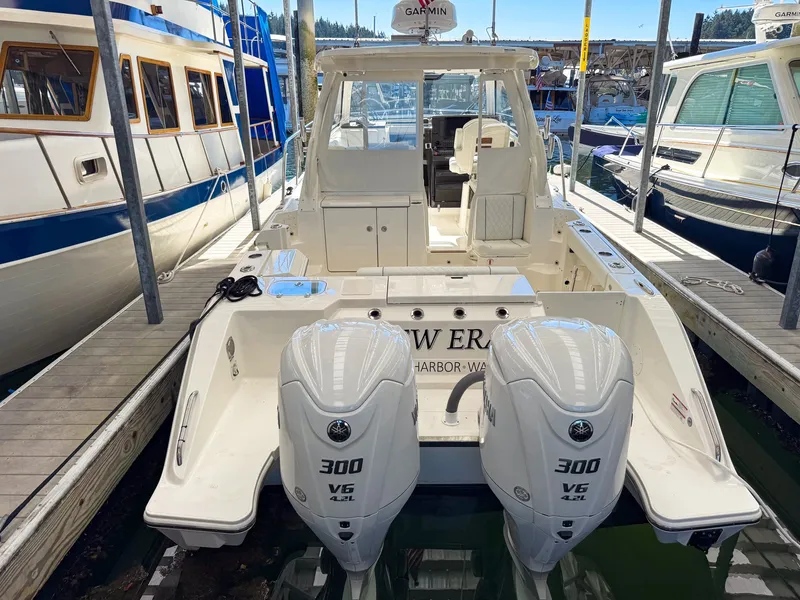 Slide: The Image of A 2026 Pursuit OS 325 Offshore boat with twin powerful outboard engines docked in a marina. - 3