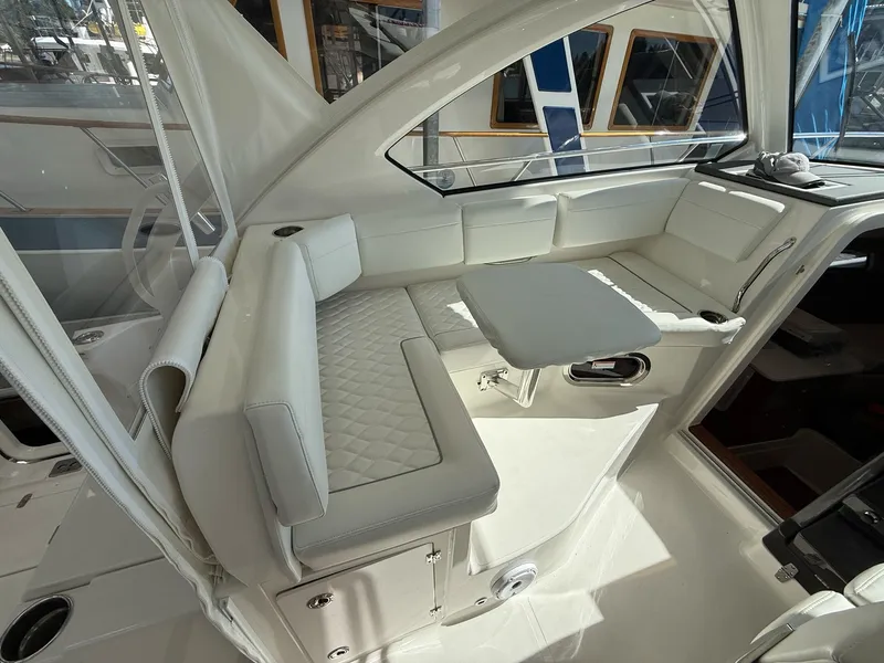 Slide: The Image of The 2026 Pursuit OS 325 Offshore cabin features elegant white upholstery and a foldable table. - 44