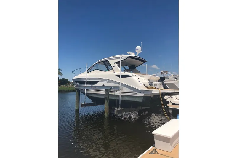The Image of 2018 Sea Ray Sundancer 350 Coupe yacht docked on a lift under clear blue skies. - 1