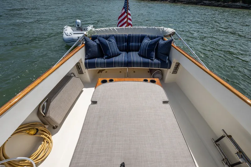 Slide: The Image of Hinckley Picnic Boat 36 Classic 2000 with cushioned seating and American flag on calm water. - 13